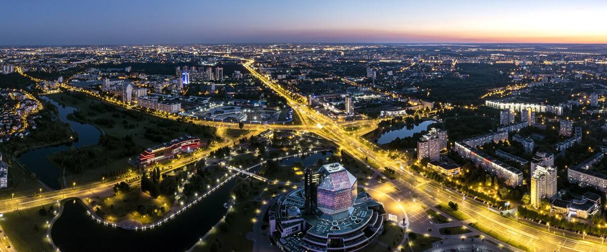 A cityscape at dusk with illuminated roads, buildings, and a prominent spherical structure.