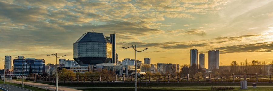Un paisaje urbano con edificios modernos y un rascacielos de diseño curvo al atardecer.