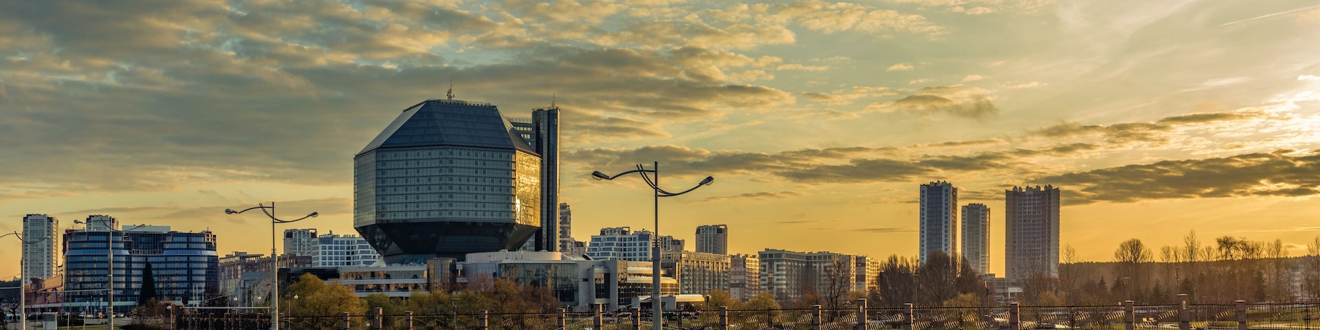 Un paisaje urbano con edificios modernos y un rascacielos de diseño curvo al atardecer.