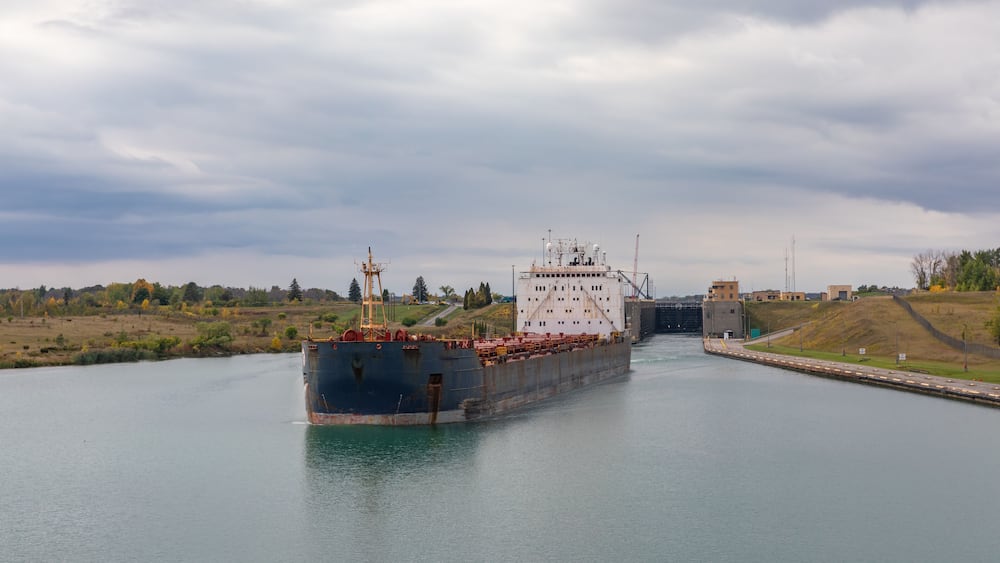 A cargo ship passing through a lock gate on a river.