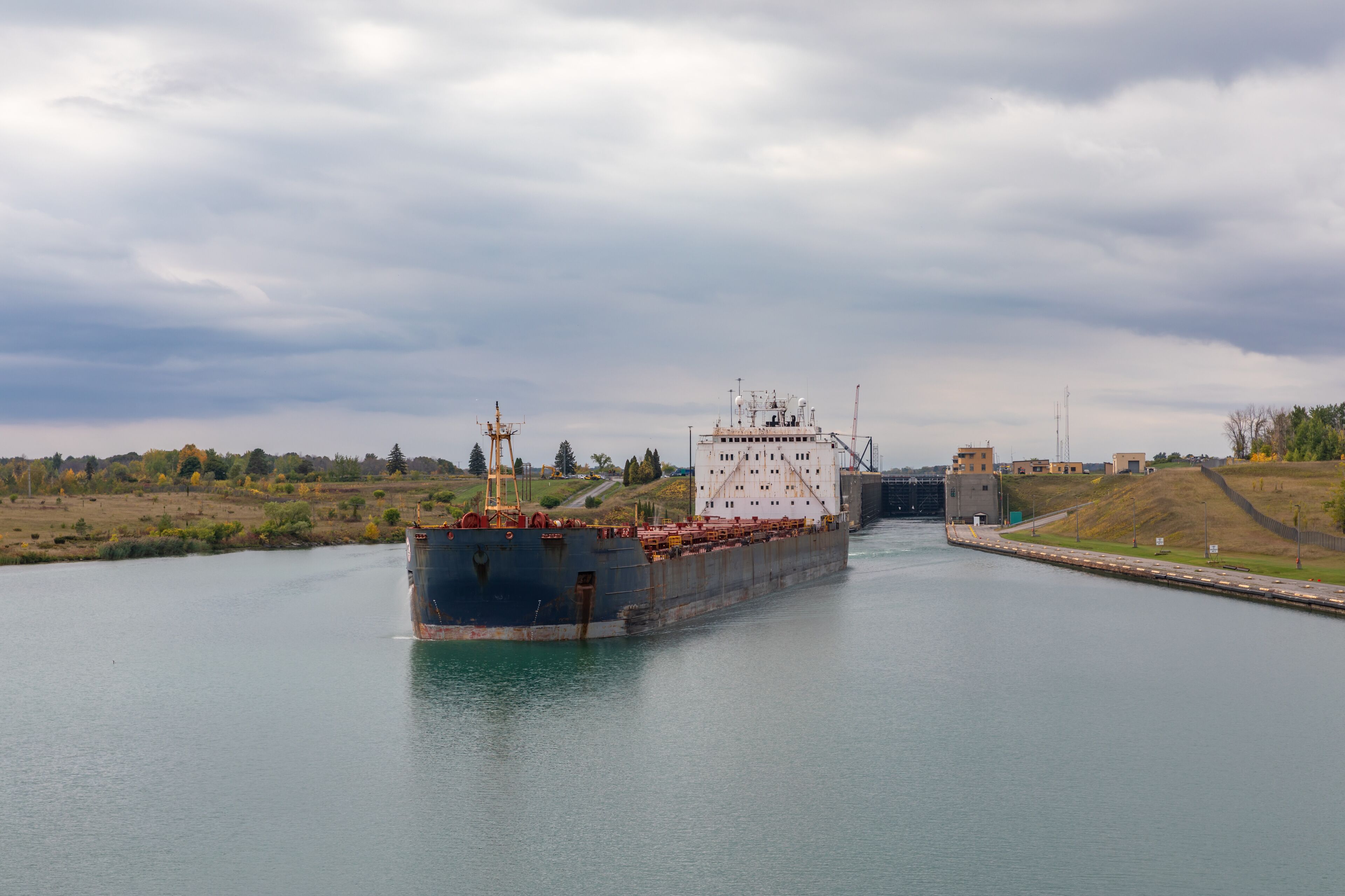 A cargo ship passing through a lock gate on a river.