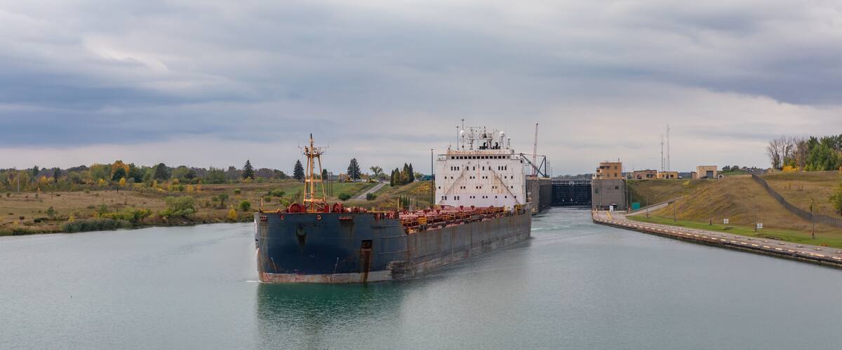 A cargo ship passing through a lock gate on a river.