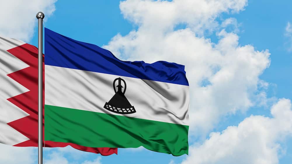 Bahrain and Lesotho flag waving in the wind against white cloudy blue sky together. Diplomacy concept, international relations.