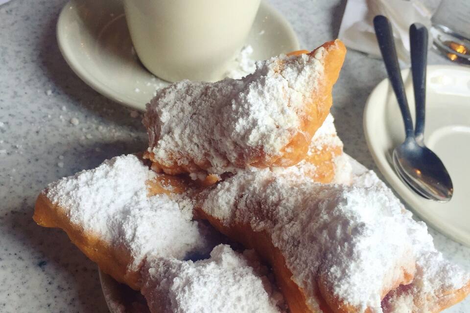 Um prato de doces em pó com uma xícara de café sobre uma mesa.