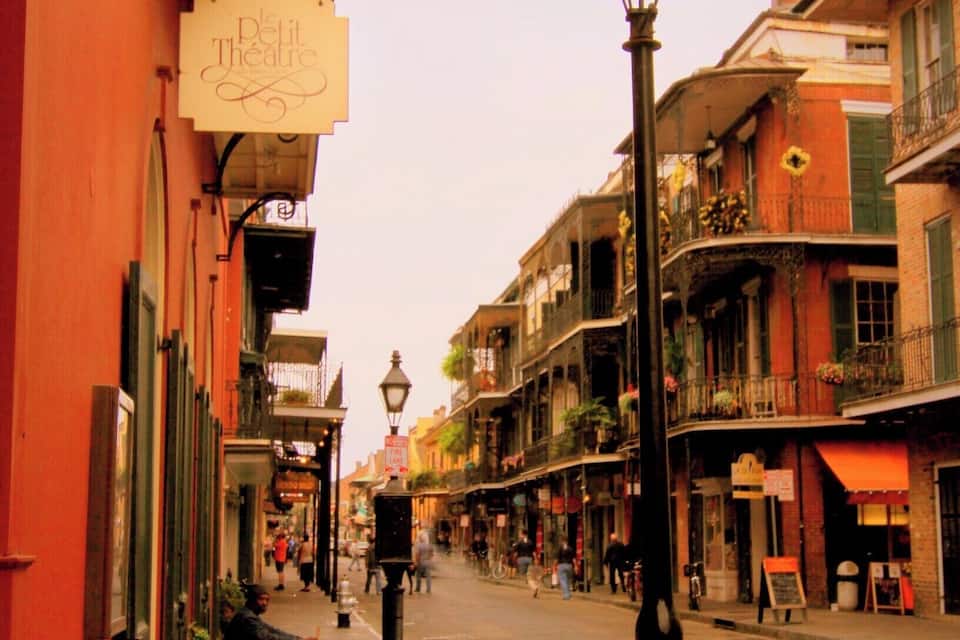 A narrow street with buildings on either side, a street lamp, and a sign for 'Petit Theatre'.