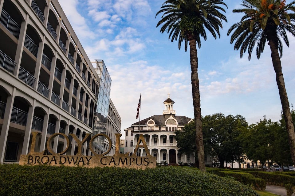 A sign reading "BROADWAY CAMPUS" with a modern building and a historic building with a dome in the background.