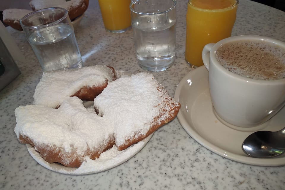 Uma mesa de café da manhã com doces, copos de suco de laranja e uma xícara de café.