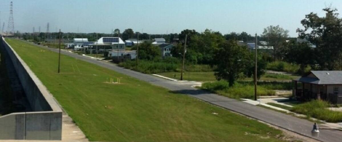 A rural landscape with a road, grassy fields, and a small building.