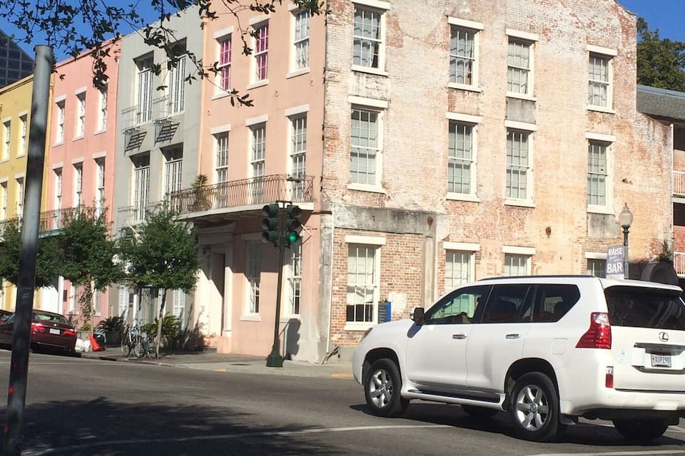 A white SUV parked on a street with a multi-story building in the background.