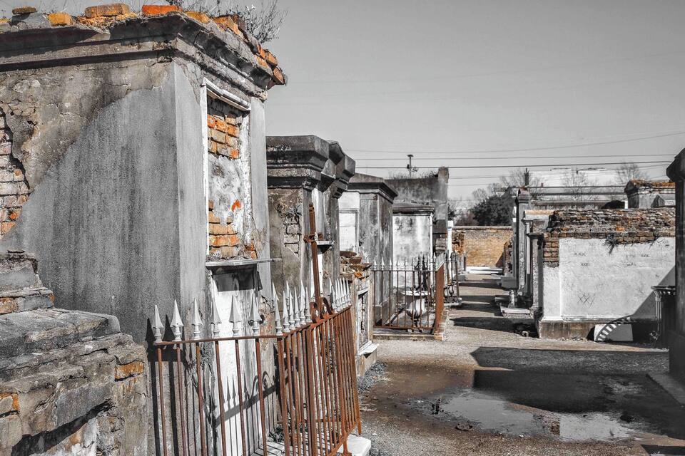 Un cimetière aux pierres tombales érodées par le temps et à la clôture métallique rouillée.