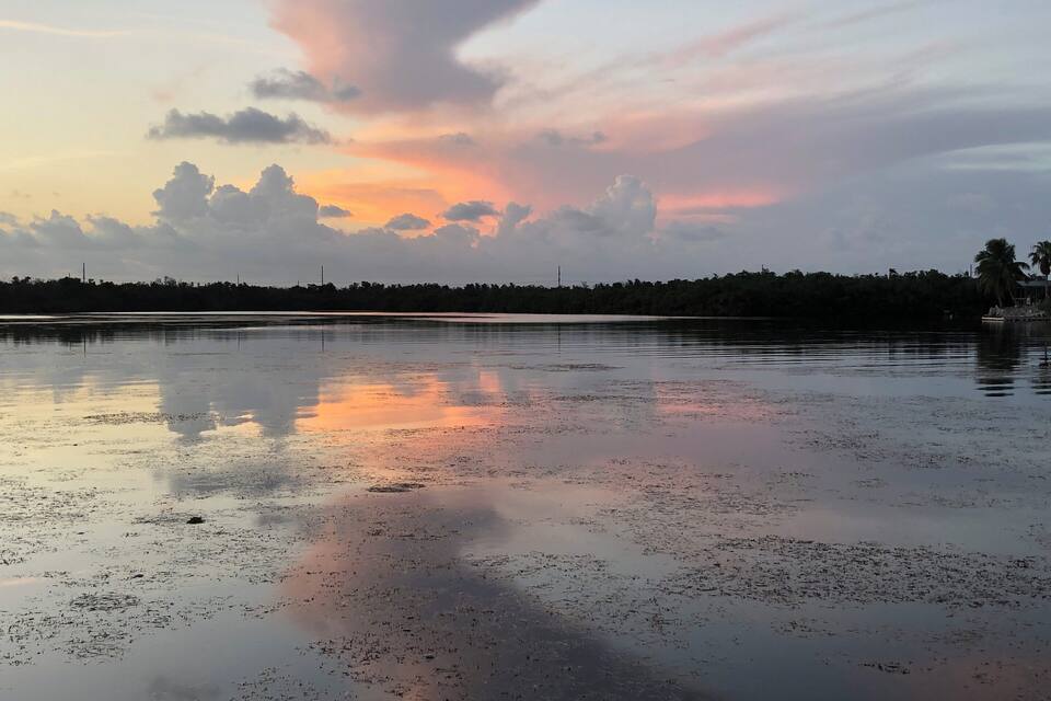 A sunset over a wet landscape with a reflection of the sky.