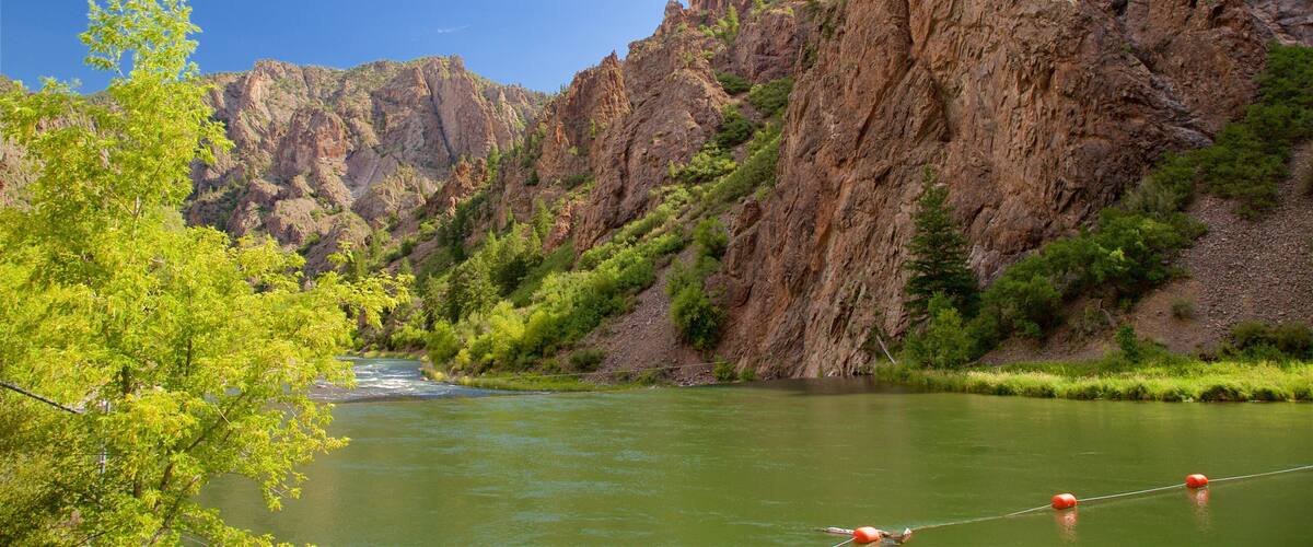A river flowing through a canyon with steep rocky cliffs and green vegetation.