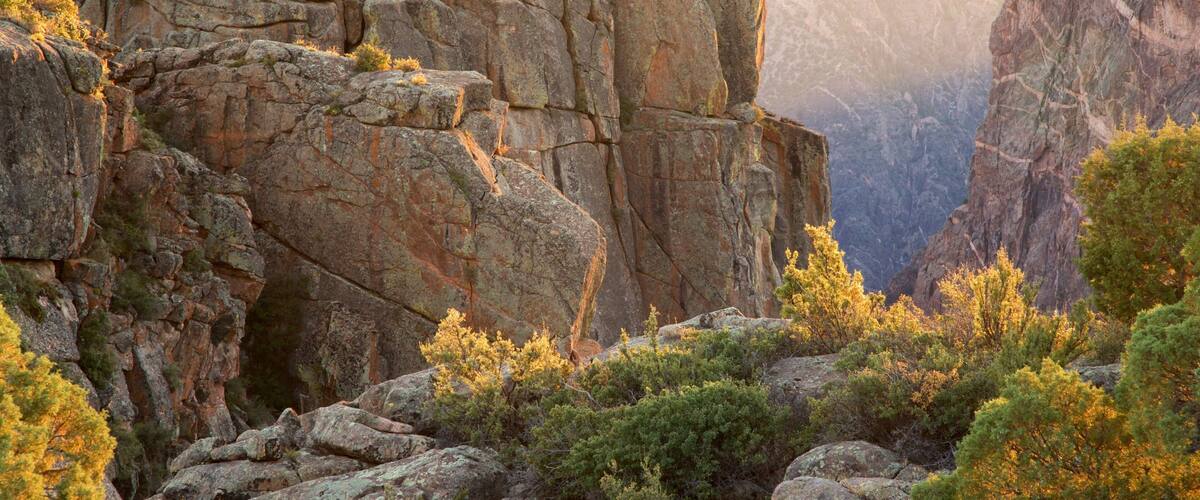 A rugged mountain landscape with rocky cliffs and dense greenery.