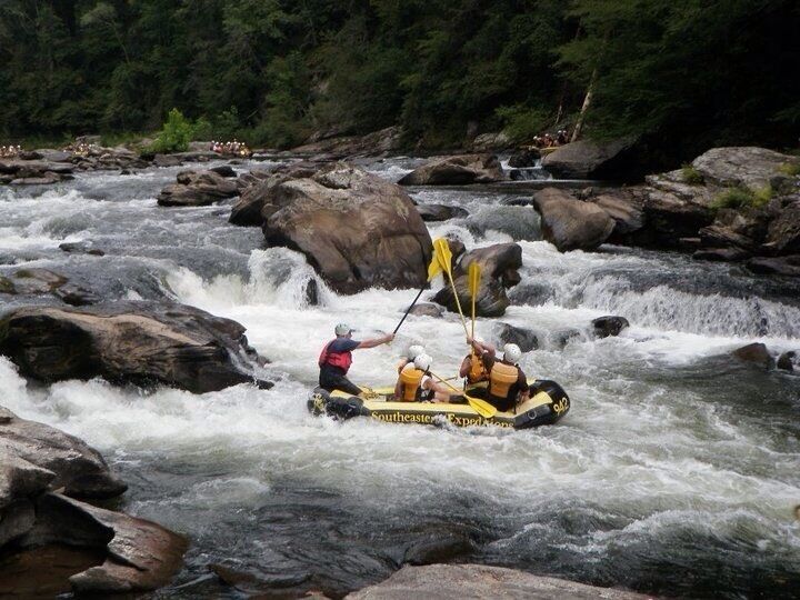 Un viaje de rafting en aguas bravas por un río con rocas grandes y rápidos.