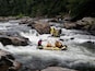 A white-water rafting trip on a river with large rocks and rapids.