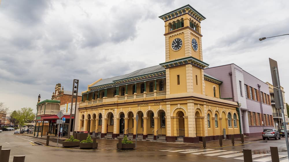 A historic post office with a clock tower, arched windows, and a green roof.