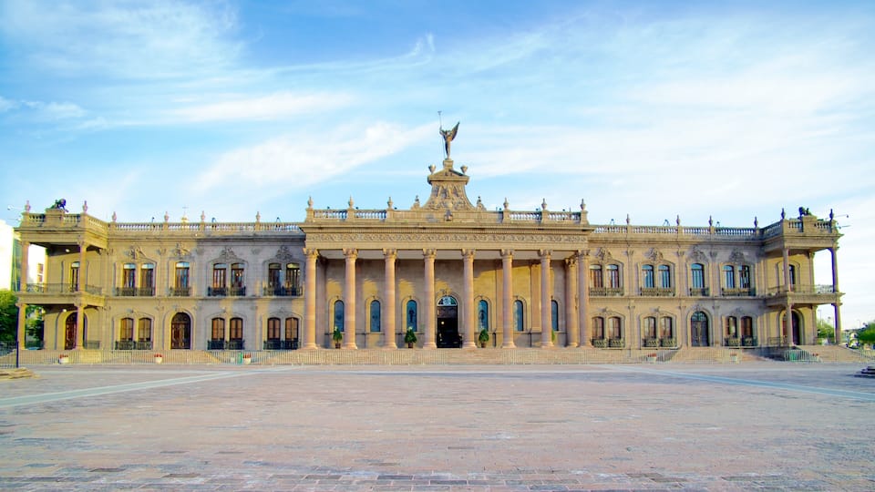 A grand, ornate building with multiple arches and columns, a central entrance, and statues on the roof.