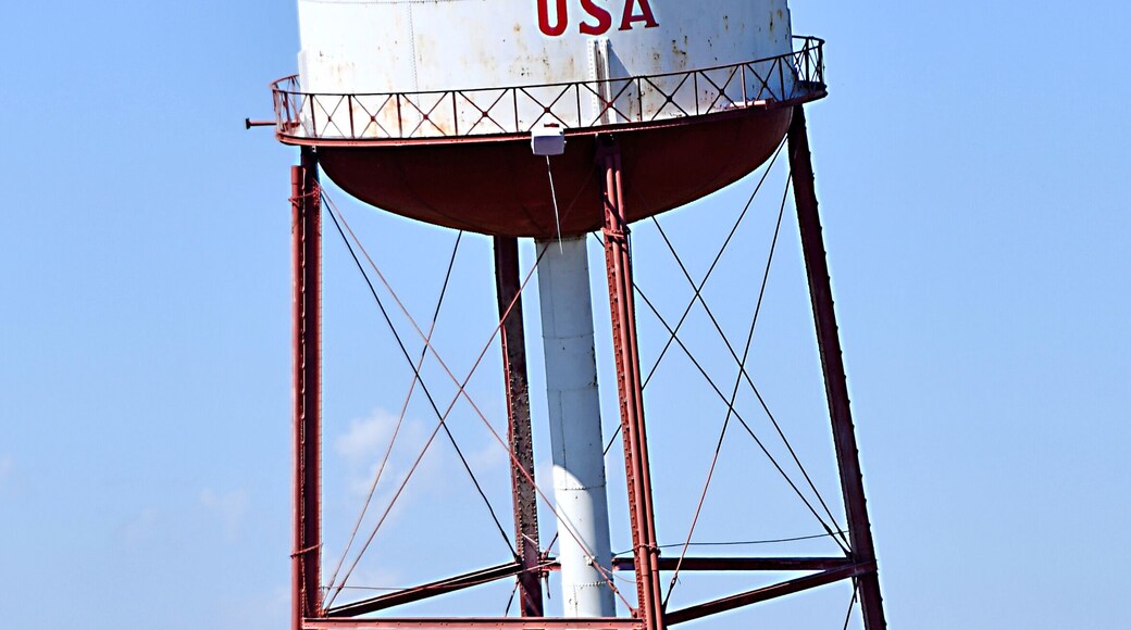 This water tower slanted at an uncomfortable angle off the old Route 66 was an ingenious marketing ploy.
Despite a population of 574 residents and its location in the middle of nowhere, the town of Groom, Texas has nearly as many unique attributes as it does people.
These include a small stretch of the original Route 66, the site of the plot of Cross Canadian Ragweed’s song “42 miles,” the seventh-largest freestanding cross in the world (at 190 feet), and a strange leaning water tower slanted at an uncomfortable angle.
This water tower lies right alongside the former path of Route 66, which has since been paved over to create US Interstate 40. During the early and mid 20th century, passersby on the Mother Road were intrigued by the severe tilt of the tower, asking themselves what on Earth could have caused it. A crashing plane? An earthquake? A giant tornado?
In reality, it was the work of a heavy-duty vehicle and a bulldozer. Ralph Britten, a man who wanted to start up a truck stop and restaurant off Route 66 in Groom, bought the water tower from the town of Lefors as an ingenious marketing technique to attract new visitors. He towed the enormous thing 34 miles to Groom, wrote “Britten USA” on top, and then, using a bulldozer, elevated two of its legs off the ground, dangling them in midair without support, so that the water tower made an 80 degree angle with the ground.
This helped his business immeasurably. It would catch the eye of every passing motorist on the route for years, many of them becoming terrified that the tower was in the process of collapsing. This played right into Britten’s hand. Worried route-takers often swerved off the road and into his truck stop, shouting “watch out! That tower’s about to fall!” Britten responded that it had been like that for years, and then asked them to sit down and buy food and a drink.
Britten’s manipulation of the tower did, however, require sufficient knowledge of physics. If the water tower were completely empty or completely full, its center of mass would be directly in the middle of the can, making it topple when slanted. So Britten filled it only partially, so that the low level of water would place the can’s center of mass near its base, directly above the two supporting legs, keeping it aloft.
Unfortunately, after many years of success, Britten’s truck stop burned down in a devastating fire, closing down all sales. Despite this unfortunate event, the leaning water tower is still one of the most photographed oddities.