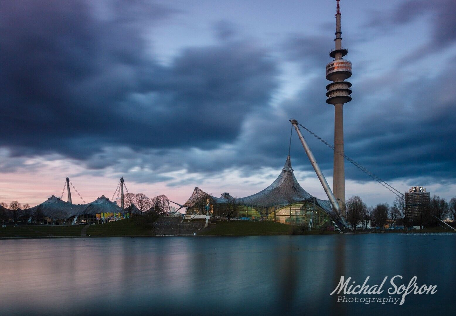 Een moderne toren met een uniek ontwerp, een grote tentachtige constructie en een rustig waterlichaam.