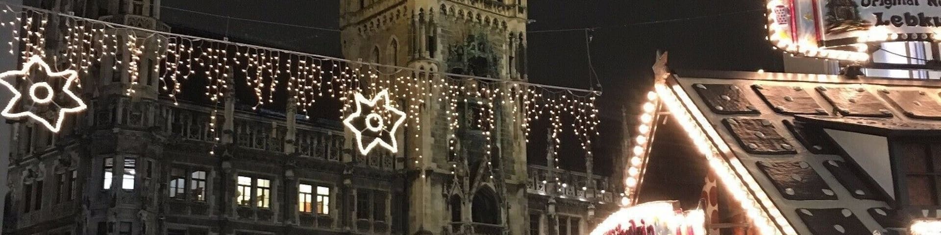A historic building with a clock tower, surrounded by festive lights and a crowd of people.