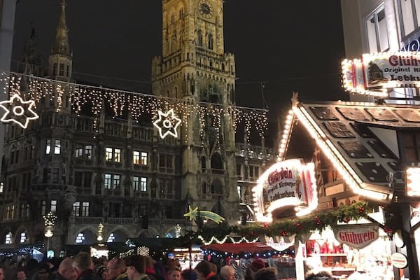Un bâtiment historique doté d’une tour horlogée, entouré de guirlandes lumineuses et d’une foule de personnes.
