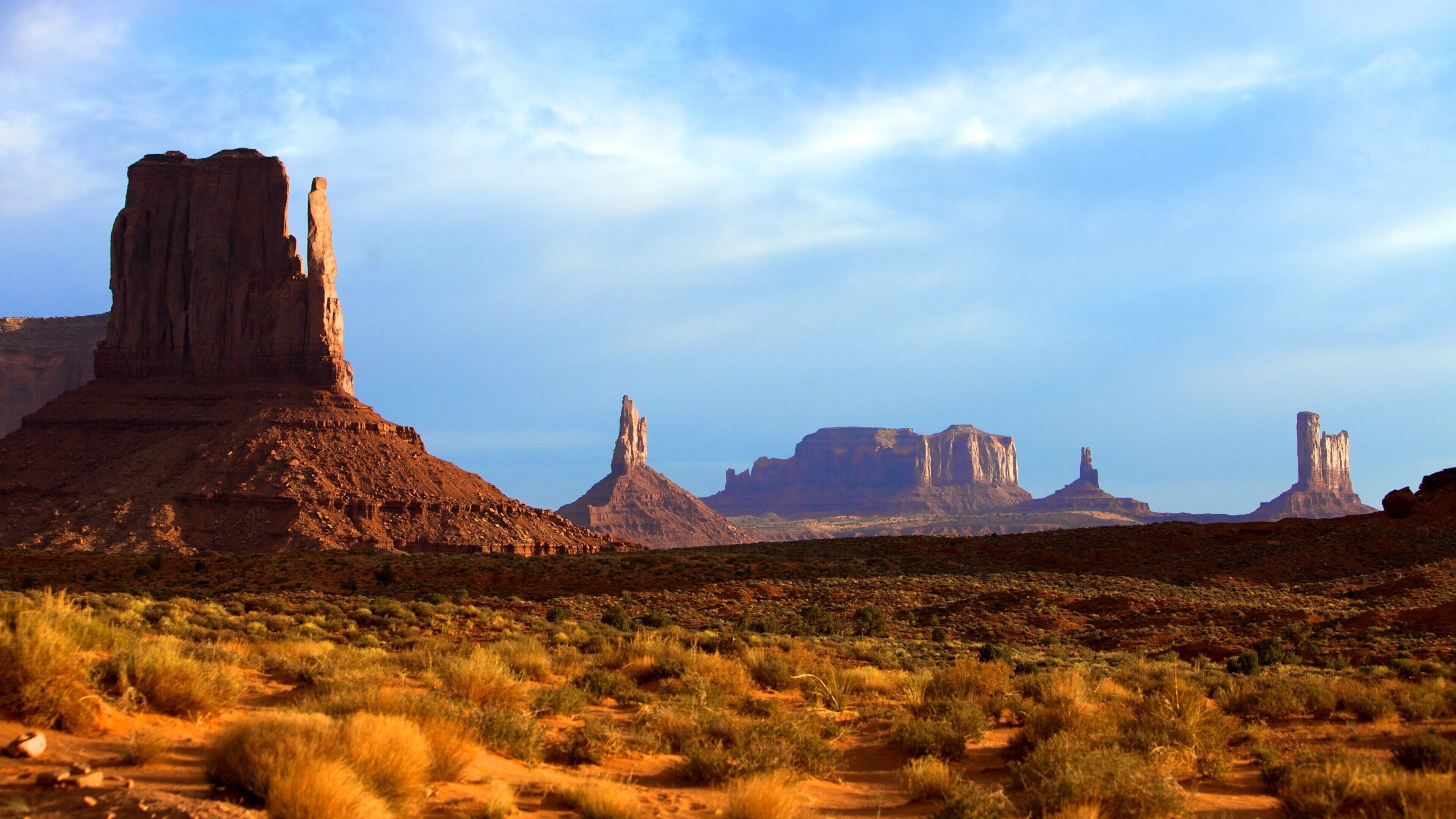 A desert landscape with prominent rock formations and sparse vegetation.