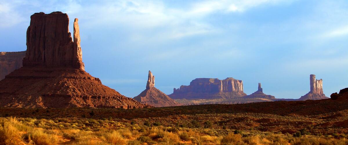 A desert landscape with prominent rock formations and sparse vegetation.