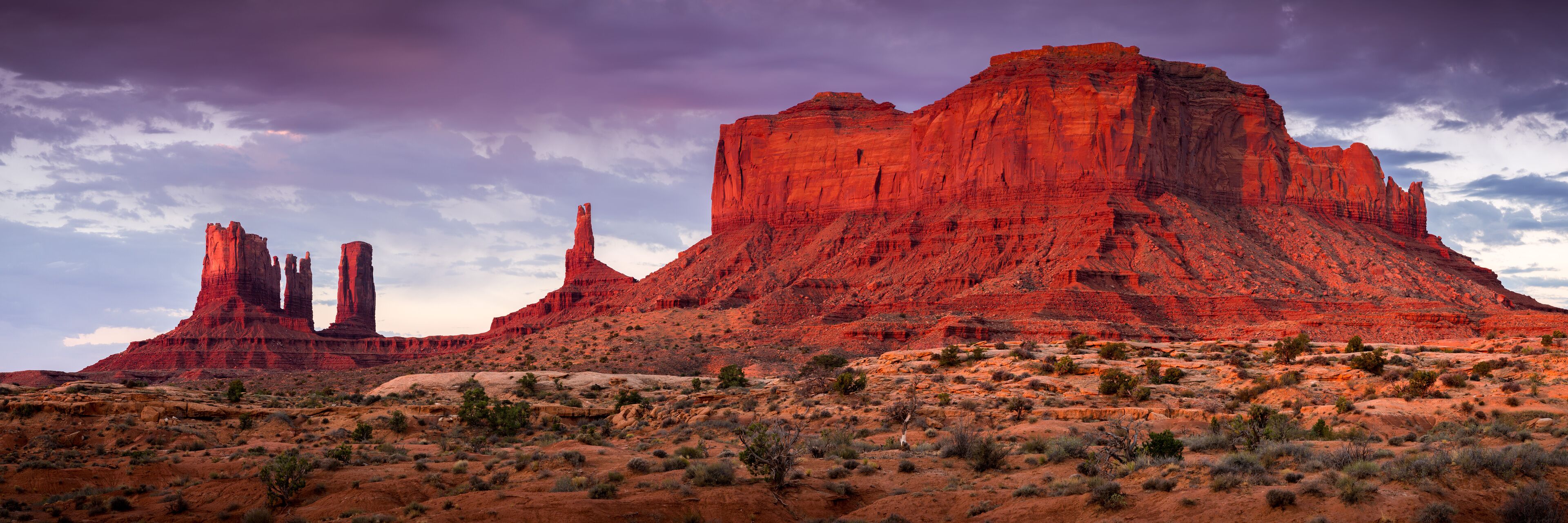 A desert landscape with red rock formations and sparse vegetation.