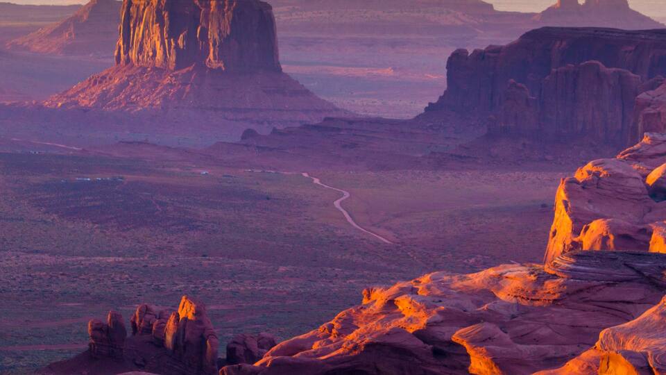 A desert landscape with prominent rock formations and a winding road.