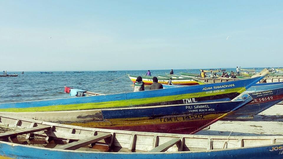 Colorful boats on a sandy beach with the sea in the background.