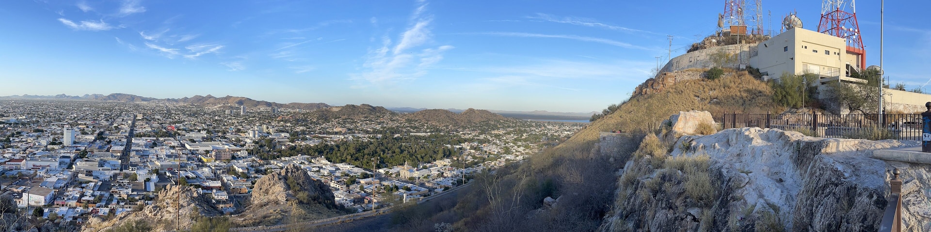 A cityscape with a prominent hill and a large building with antennas.
