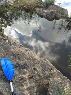 Perched on island in the river with some clouds reflecting off a pool in the rock