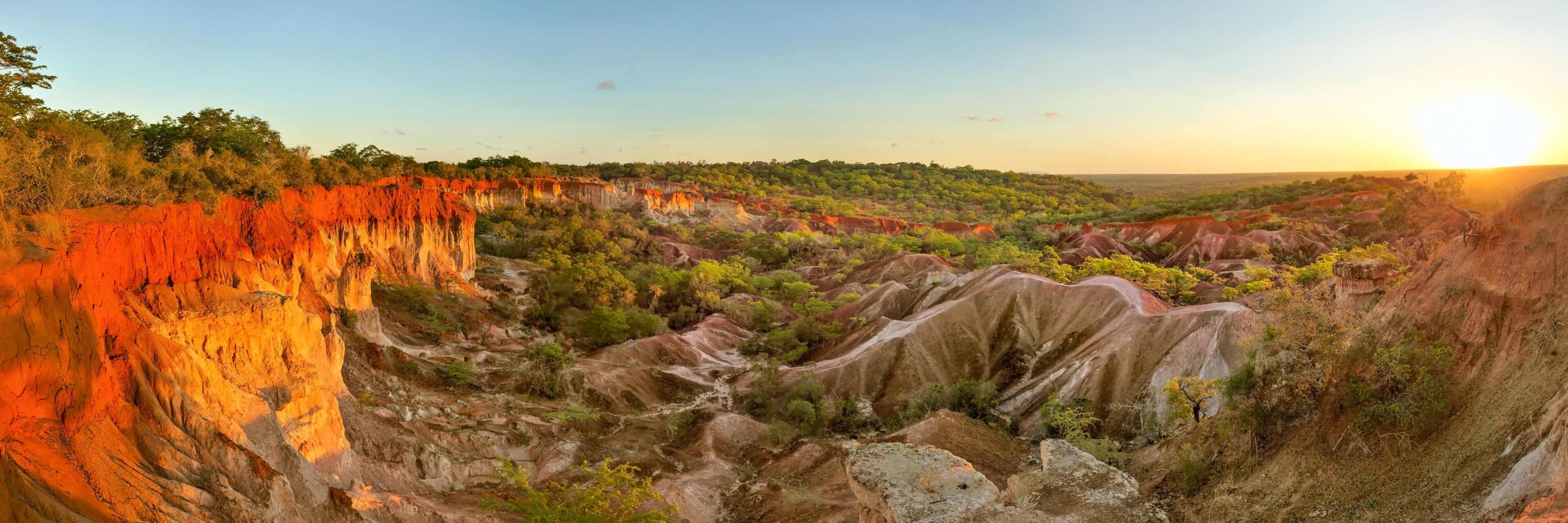 A rugged landscape with red rock formations and green vegetation.