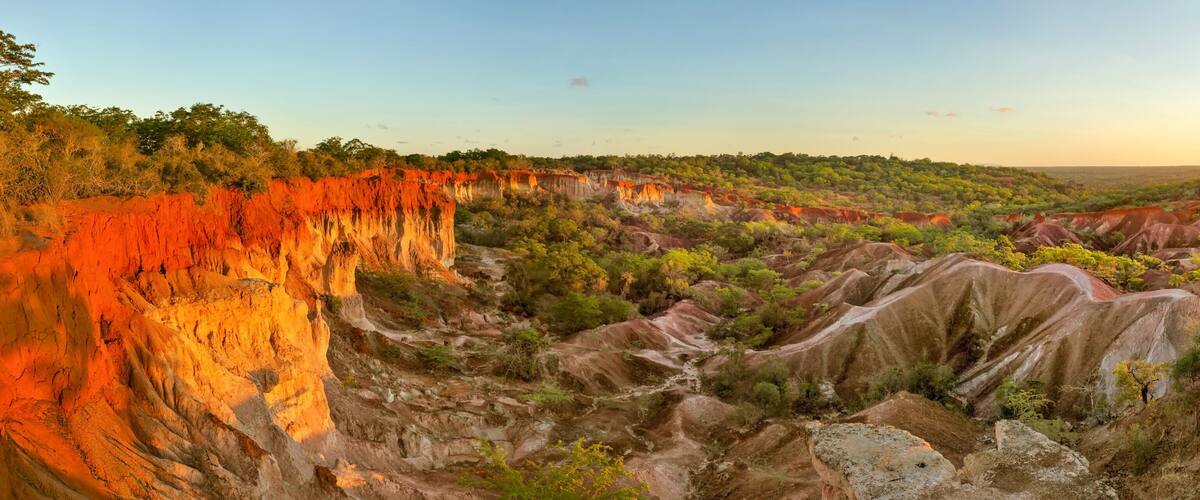 A rugged landscape with red rock formations and green vegetation.