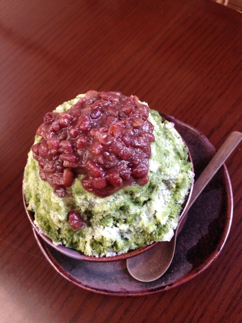 A bowl of green food topped with red beans.