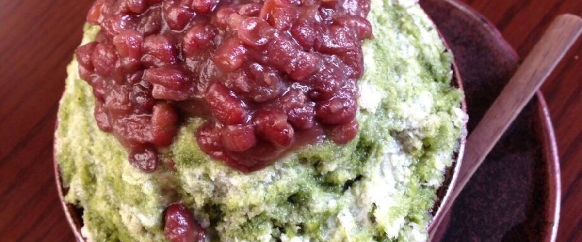 A bowl of green food topped with red beans.