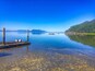A calm lake with boats, a dock, and a forested hillside.