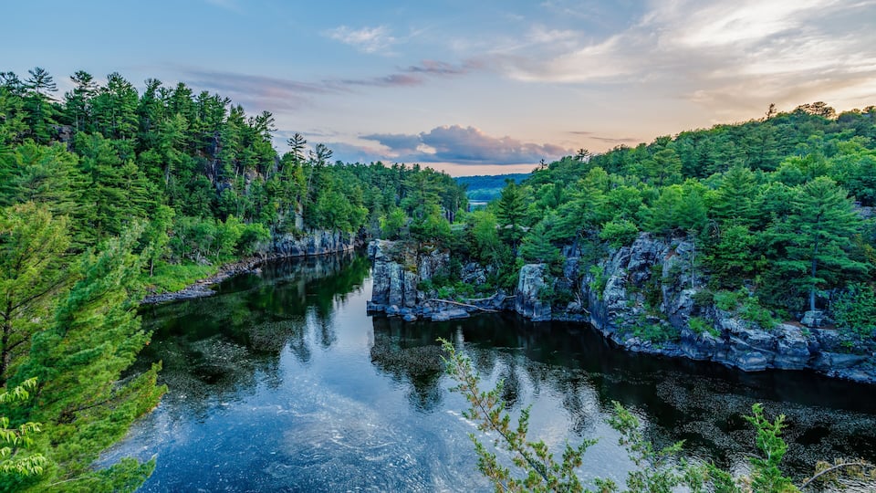 A river surrounded by dense forest and rocky cliffs.