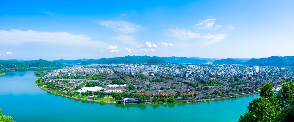 A cityscape with a river, mountains, and a bridge.