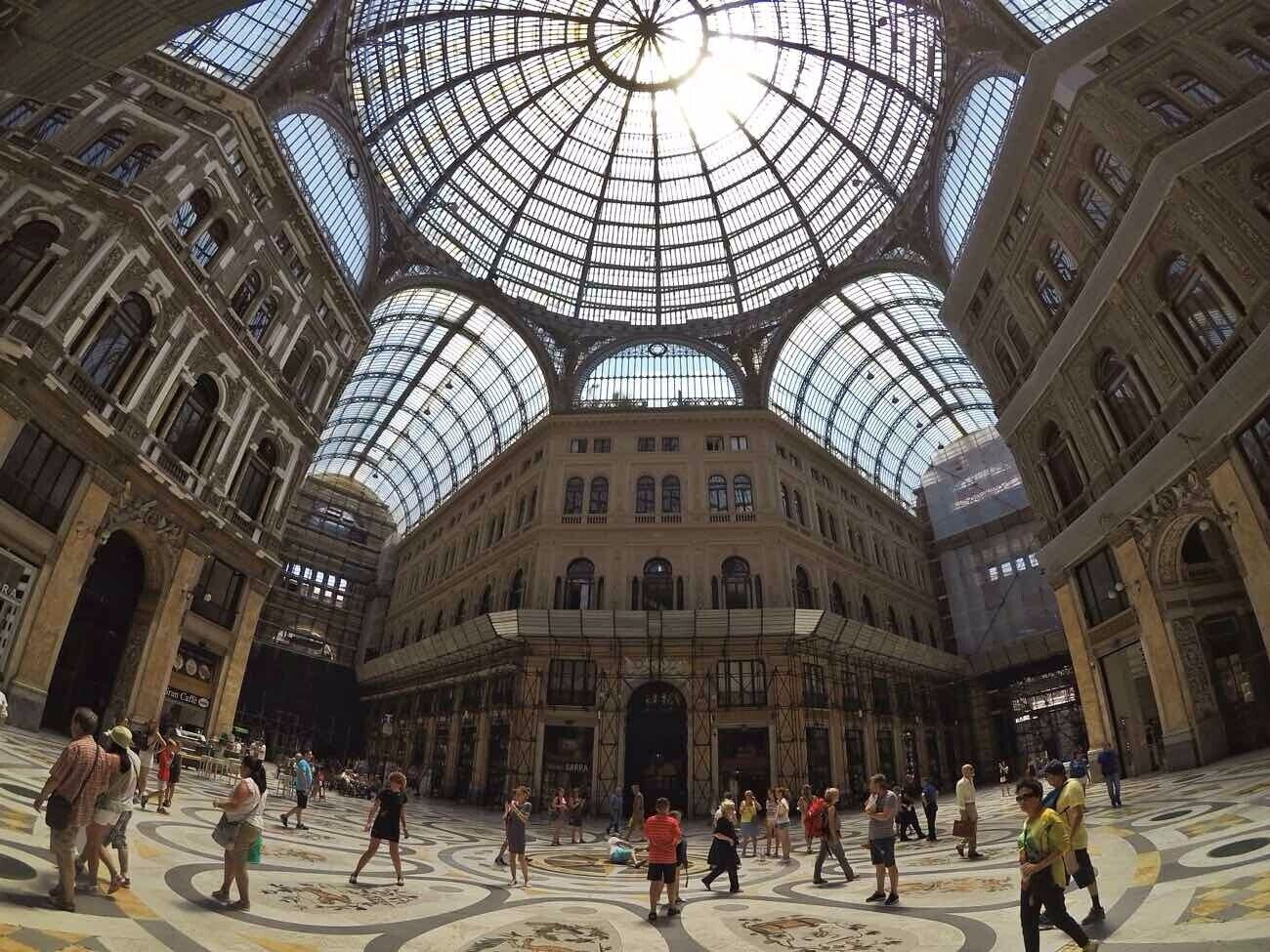 Um edifício imponente e histórico, com uma grande cúpula de vidro e arquitetura elaborada.