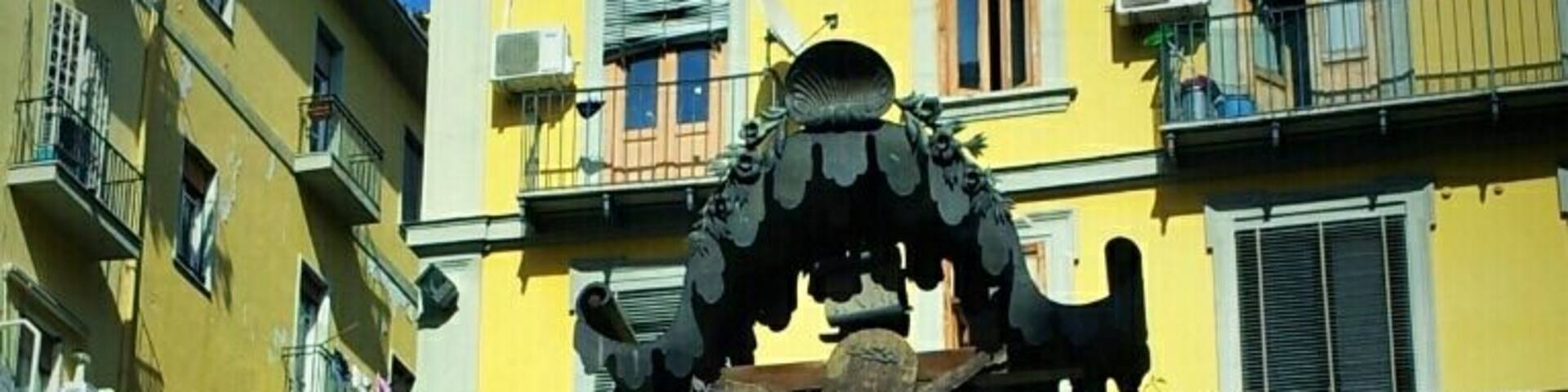 A yellow building with balconies, a statue of a crucifixion, and a street lamp.