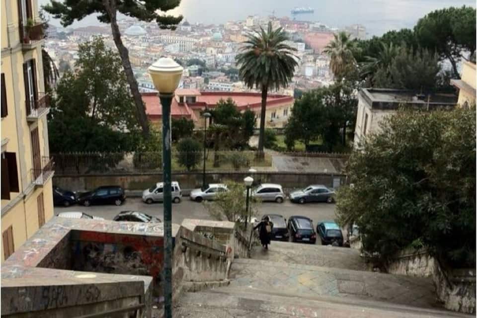Une vue urbaine avec la mer en arrière-plan, un escalier et des voitures garées.