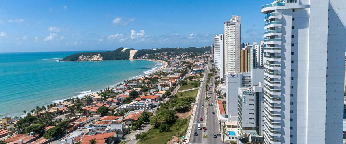 Un paysage urbain côtier avec une plage, des immeubles de grande hauteur et un ciel bleu dégagé.