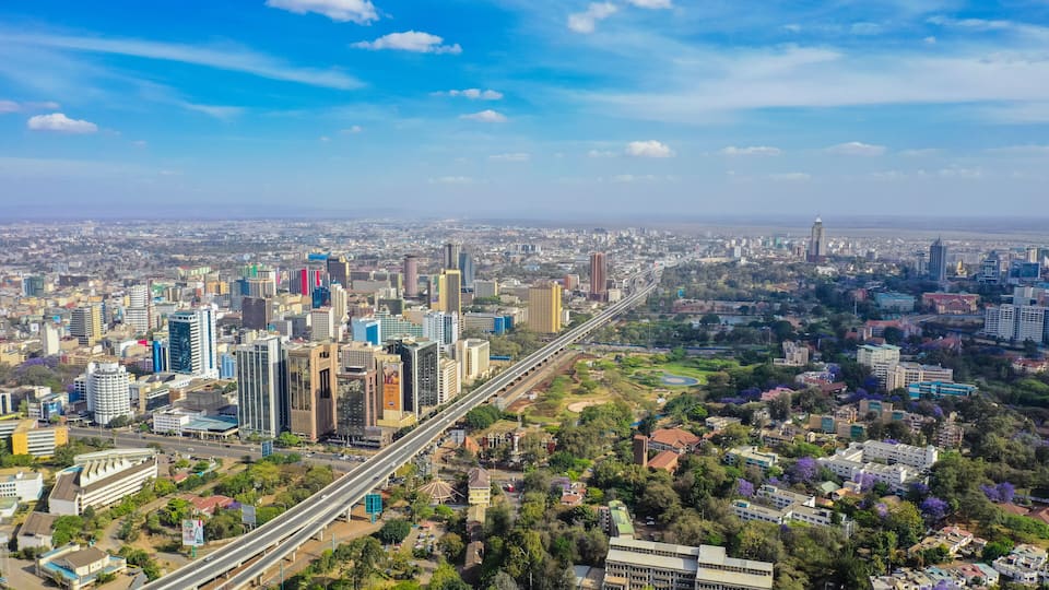 A cityscape with a prominent highway, dense urban buildings, and surrounding greenery.