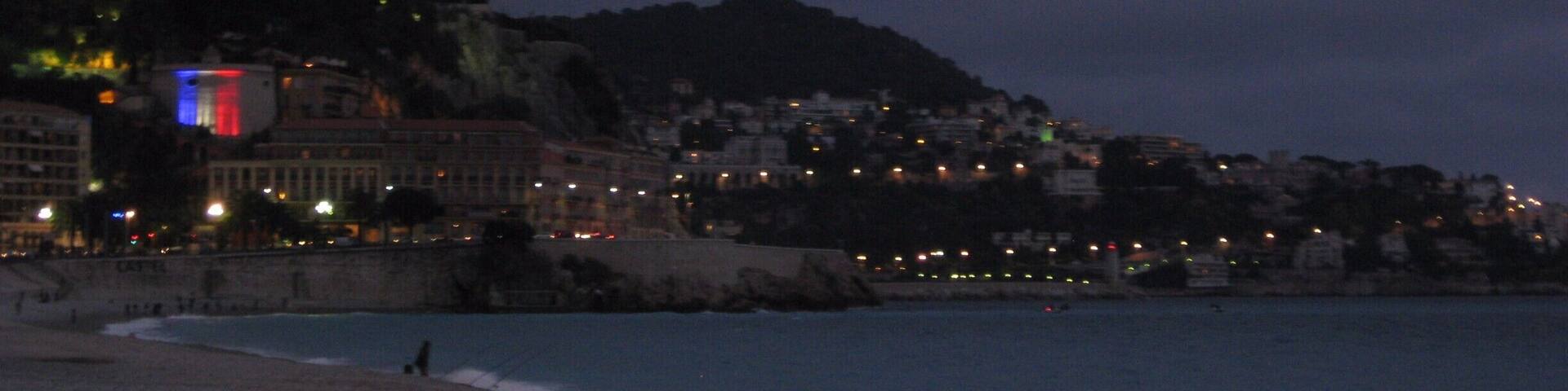 A beach at dusk with a cityscape in the background.