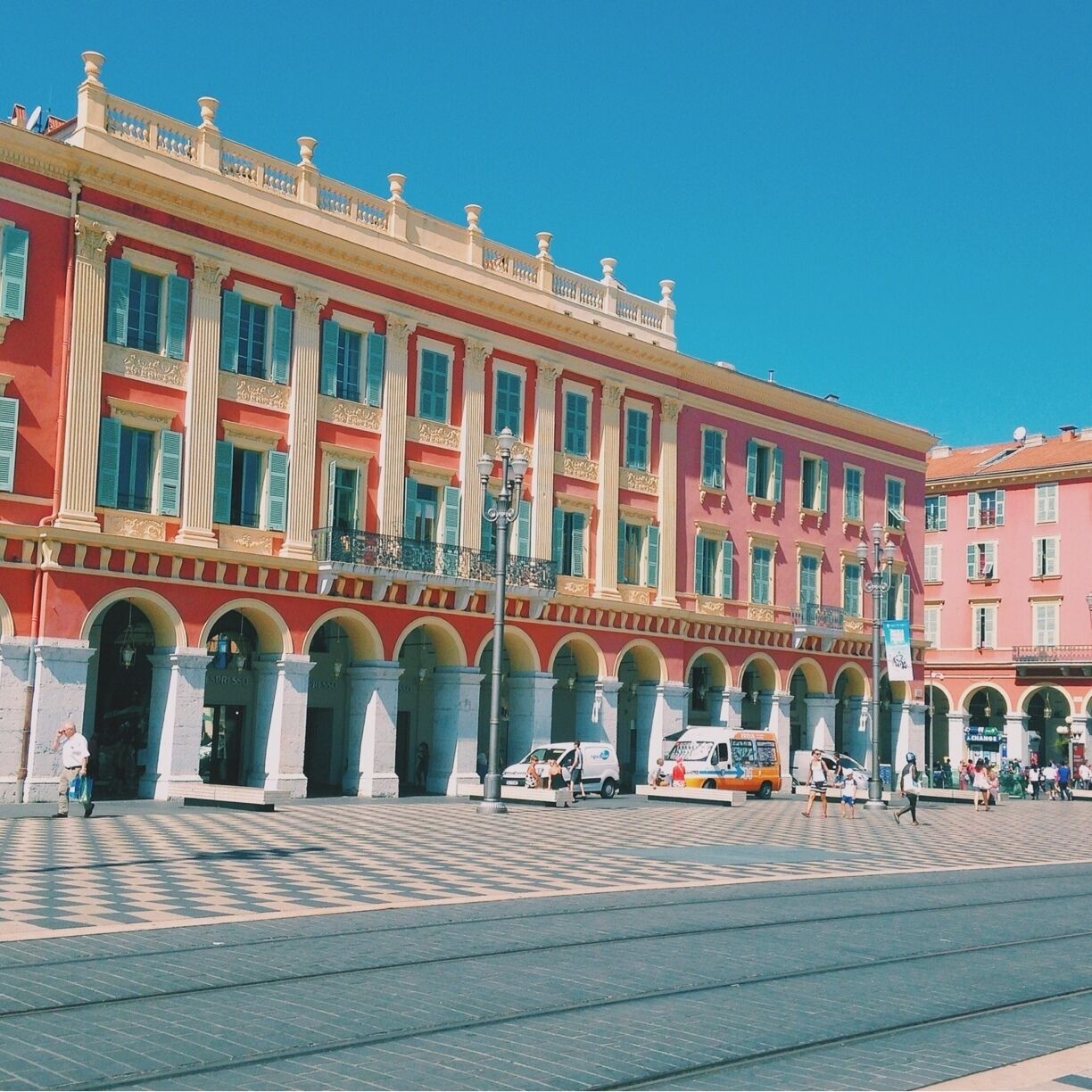 Ein historisches Gebäude mit roter und weißer Fassade, Säulen und rundbogigen Eingängen.