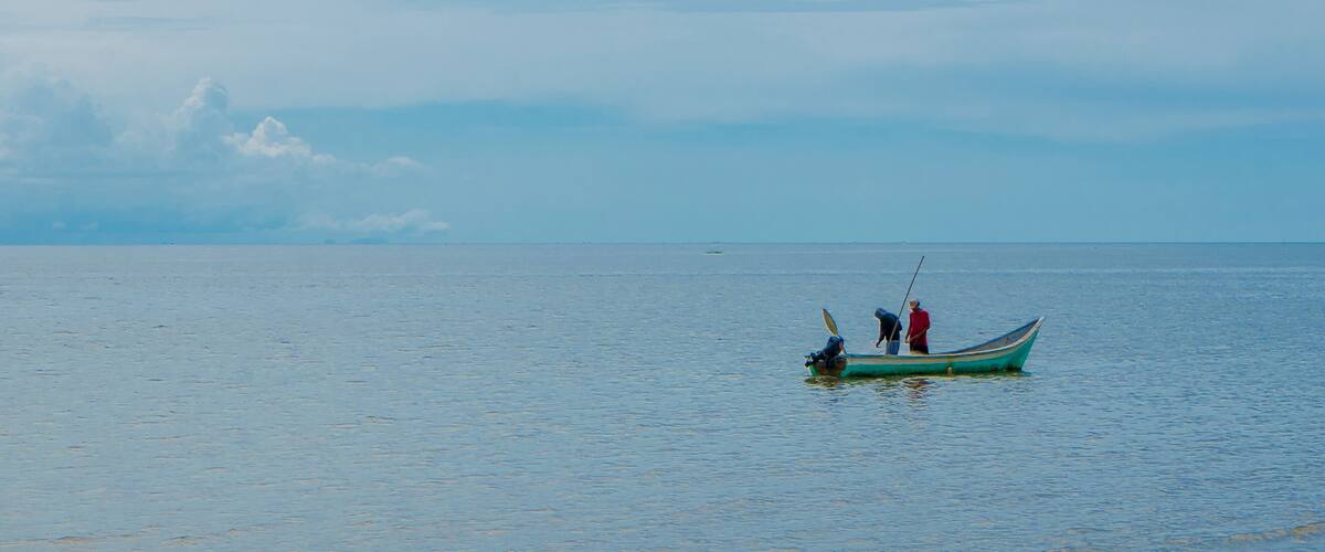 A calm sea with a small boat carrying two people.