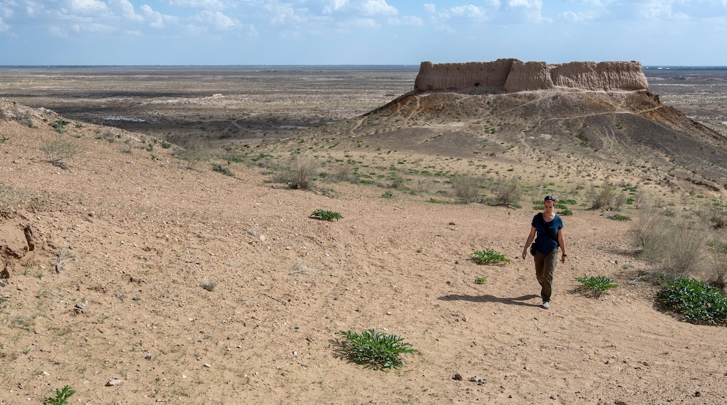 European tourist (young woman) hikes in Kyzylkum desert. Ayaz-Kala fortress (the most popular and picturesque fortress in the country). Nukus, Karakalpakstan, Uzbekistan, Central Asia.