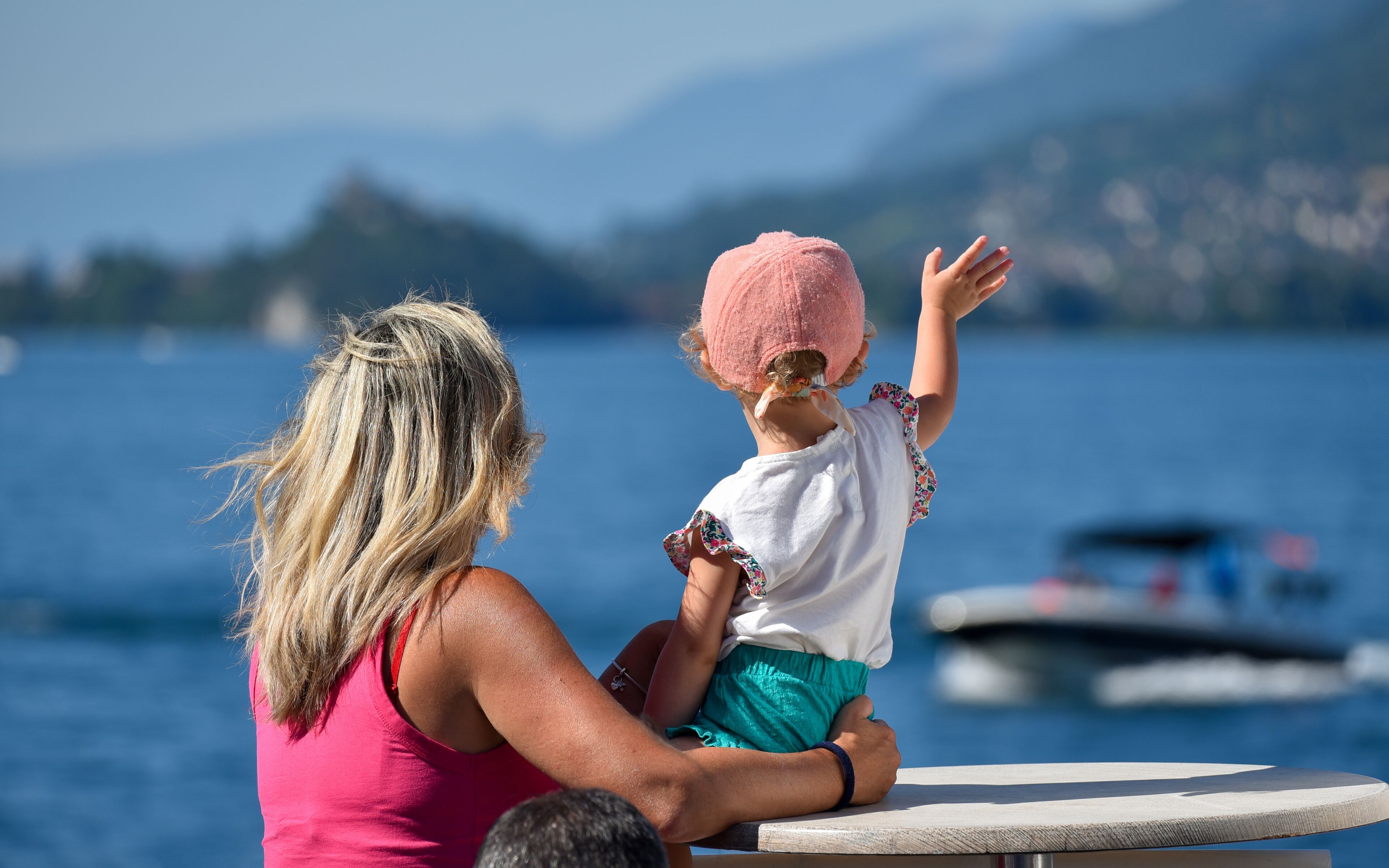 A woman and a child on a boat with a lake and mountains in the background.