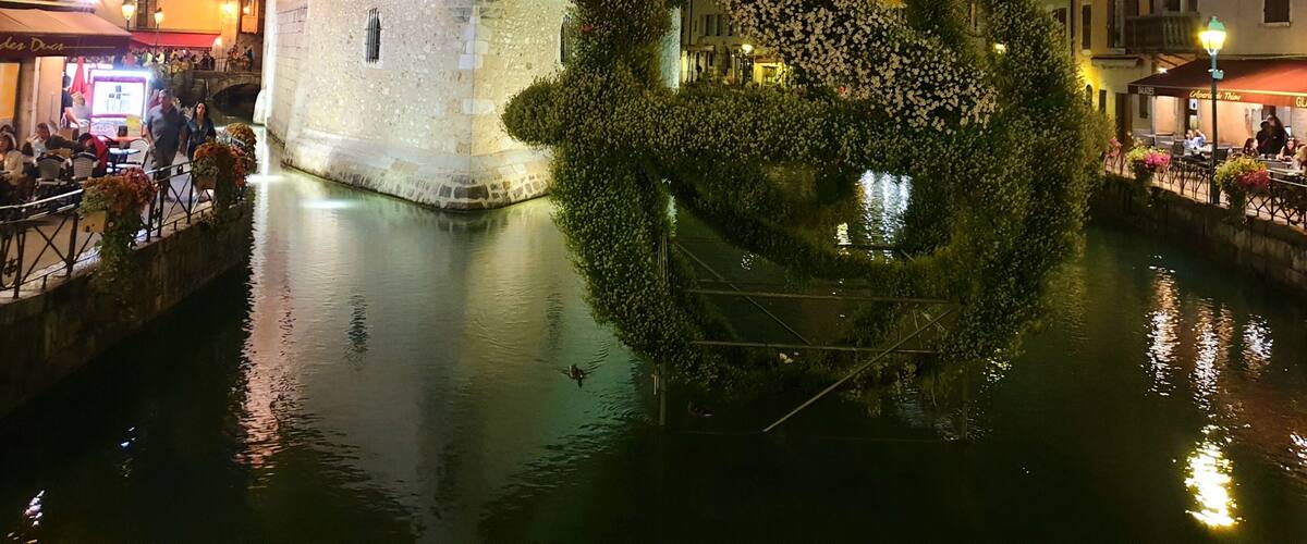 Ein historischer SteinTurm mit spitzem Dach, ein kreisrümiges Gartenbauelement und ein Kanal, der den Turm und den Garten spiegelt.